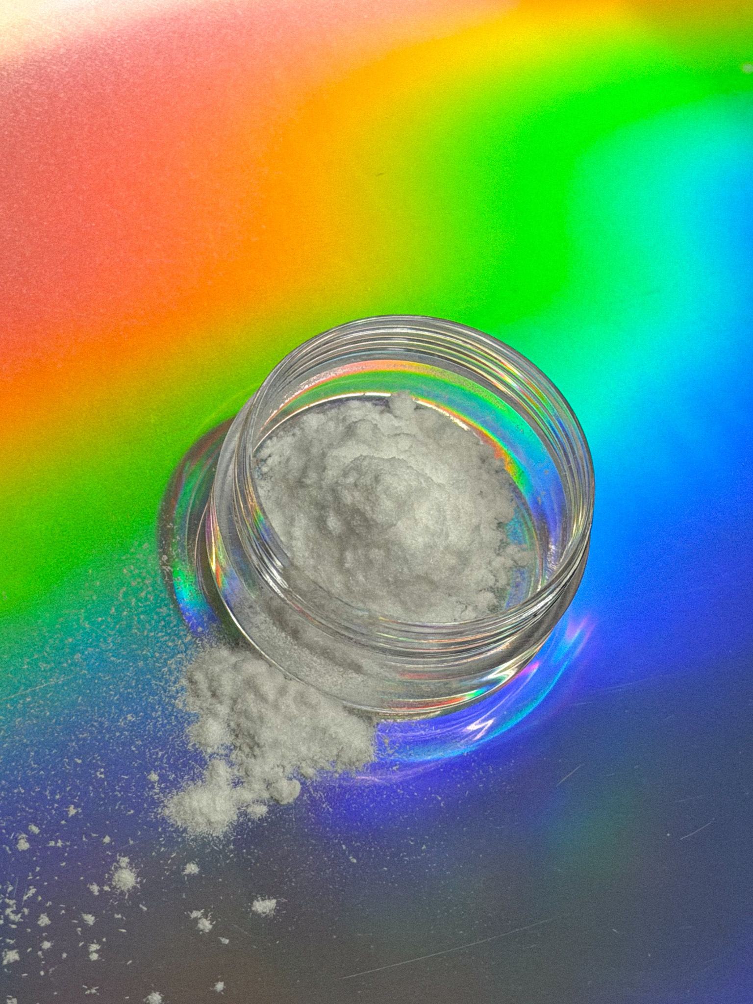 Pure Kavain Isolate powder in a clear jar with a small spill on a colorful gradient background.