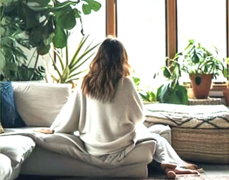 Woman that is relaxed in a room sitting on a couch with vegitation