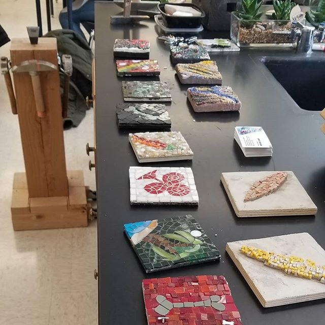 4”x4” mosaic art pieces of different designs displayed on a work table.