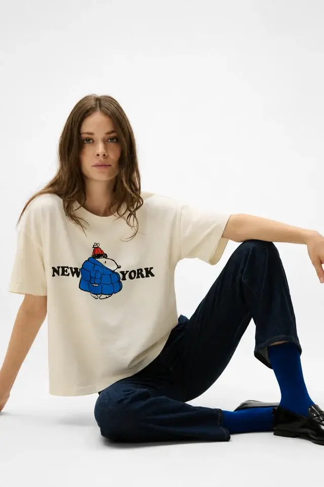Tee-shirt Snoopy New York Five White porté, avec imprimé Snoopy en bleu et inscription New York, coupe décontractée.