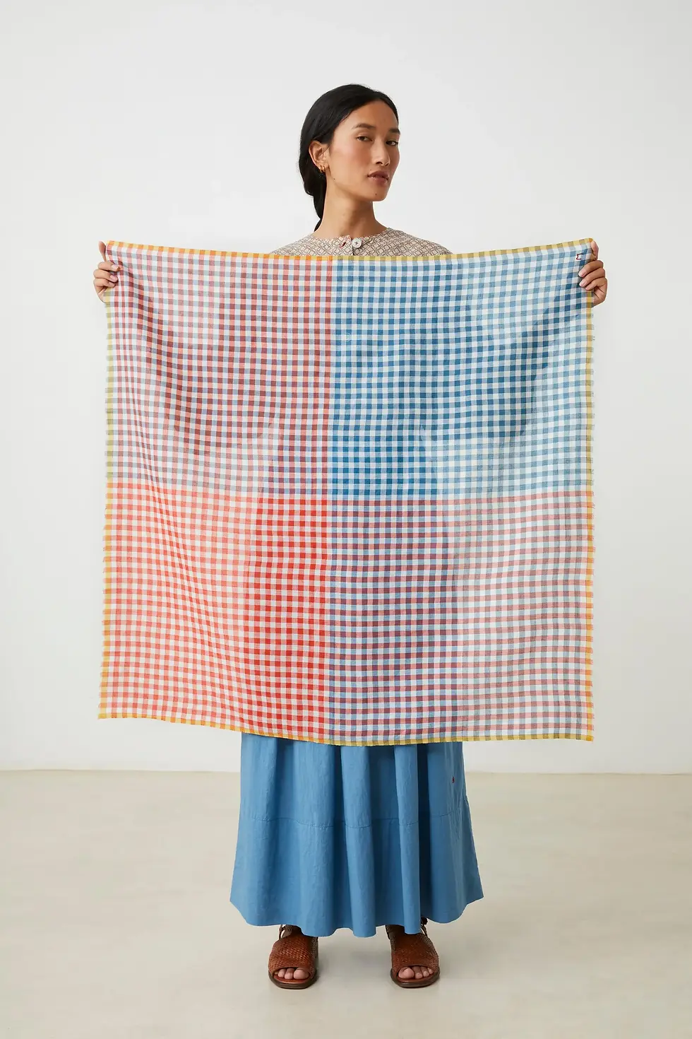 Miniature : Foulard Poem N°821 Moismont Spritz porté par un modèle femme en vue corps entier tenant le foulard ouvert par deux pointes