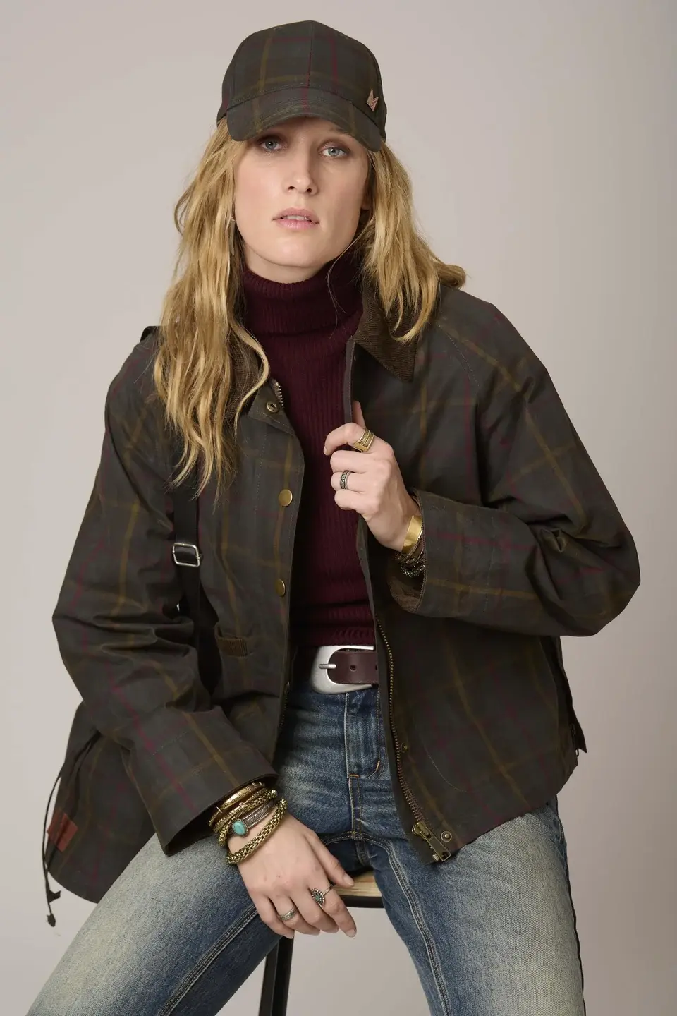 Manteau Mariela MKT porté assise, modèle tenant la partie boutonnée du manteau d’une main