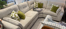 Beige corner sofa with green and patterned cushions.