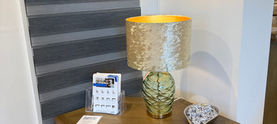 Corner wooden cabinet with a lamp and window blind.