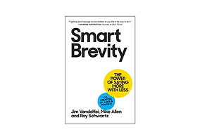 The image shows the cover of the book 'Smart Brevity' by Jim VandeHei, Mike Allen, and Roy Schwartz. The cover's background is white with the title 'Smart Brevity' prominently displayed in vertical black letters on the left side. A large yellow circle on the right side contains the subtitle 'The Power of Saying More with Less' and a caption reading 'Co-Creators of Axios & POLITICO.' At the bottom, the authors' names are listed. Above the title, there's a quote by Arianna Huffington, founder & CEO, Thrive, stating, 'If getting your message across matters to you, this is the way to do it.' The overall design is simple and impactful, emphasizing the theme of brevity.
