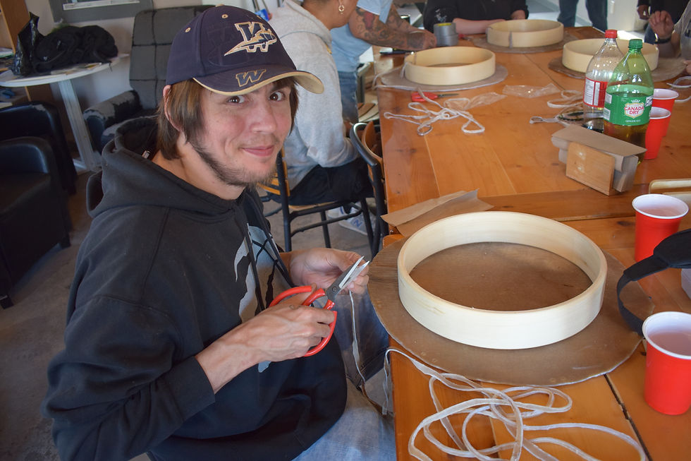 Man using scissors at an Indigenous drum-making workshop.