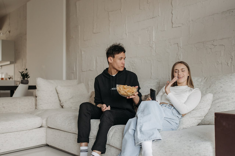 Casal relaxando no sofá com tigela de salgadinhos, representando o desafio da alimentação, nutrição e comportamento alimentar para pessoas com diabetes.