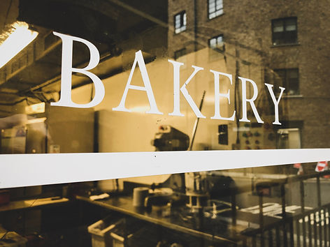 Looking through a bakery window from the outside. Storefront sign on the glass with reflec