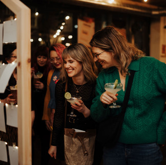 Friends of Curated Makers smiling whilst looking at the photowall.