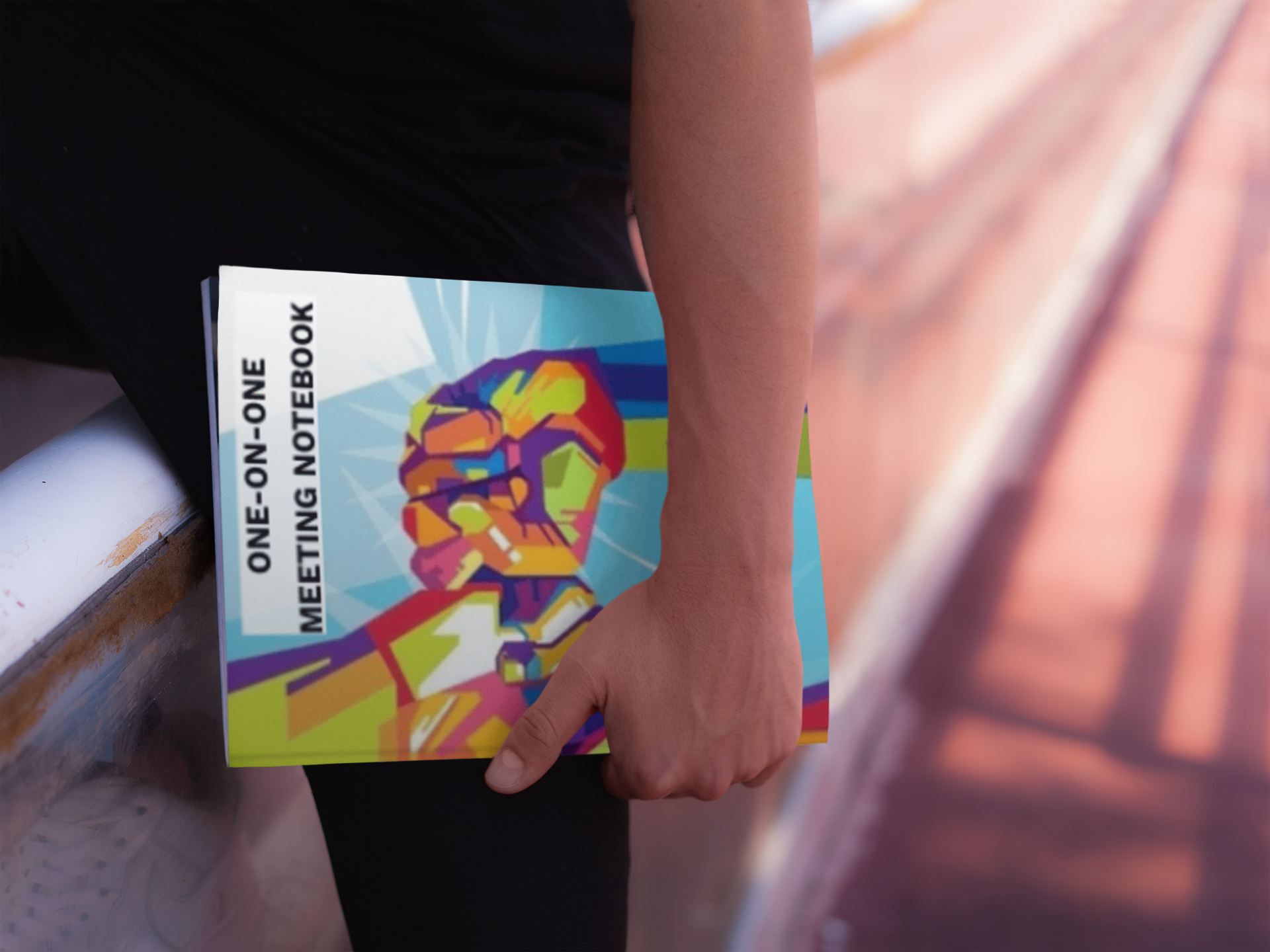 Person holding a colorful one-on-one meeting notebook while walking on a track outdoors