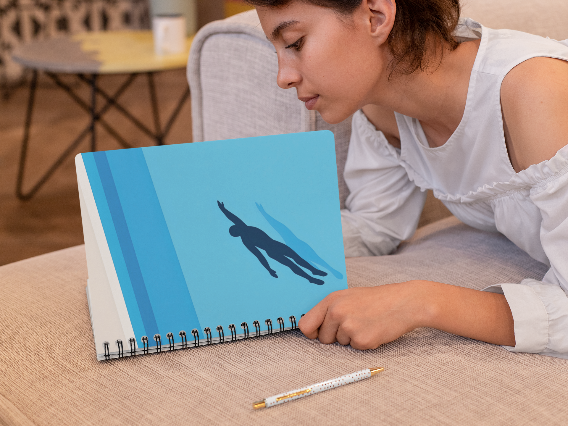 Woman writing in blue spiral swim notebook at table