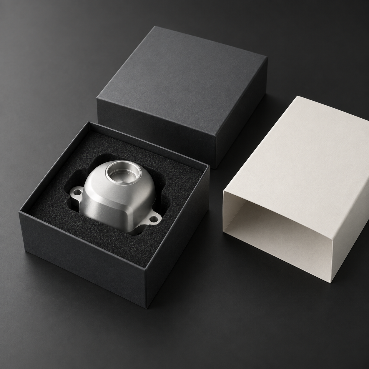 Studio packaging concept with a silver component in a fitted foam insert, graphite presentation box and ivory sleeve