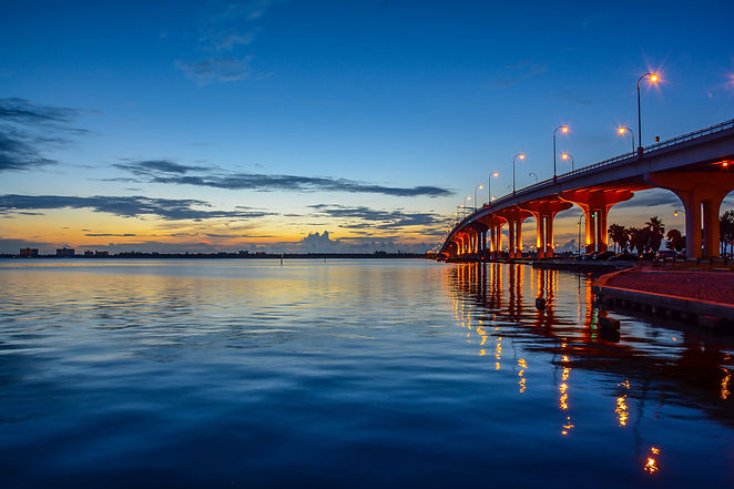 Scenic view of dawn with a curving causeway bridge lit with street lights reflecting in th