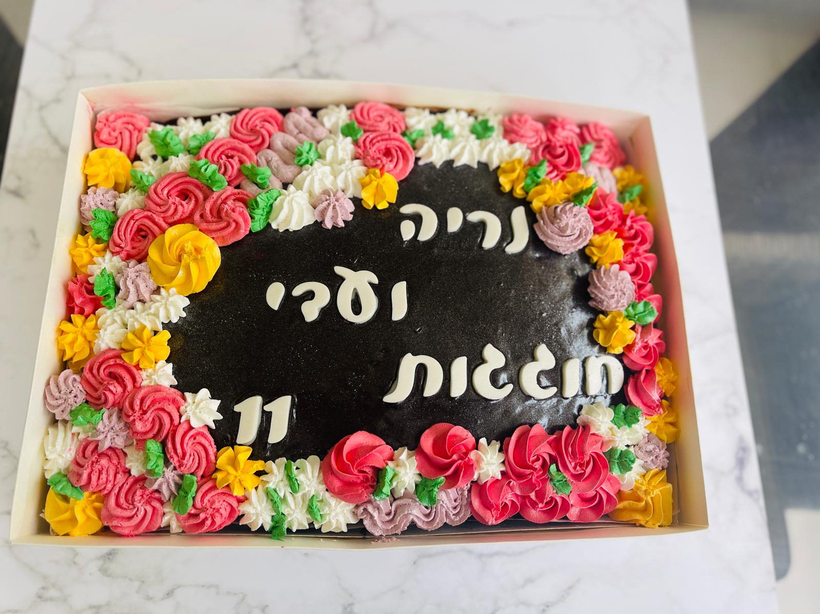 עוגת שוקולד מלבנית עם כיתוב ועיטורי פרחים צבעוניים