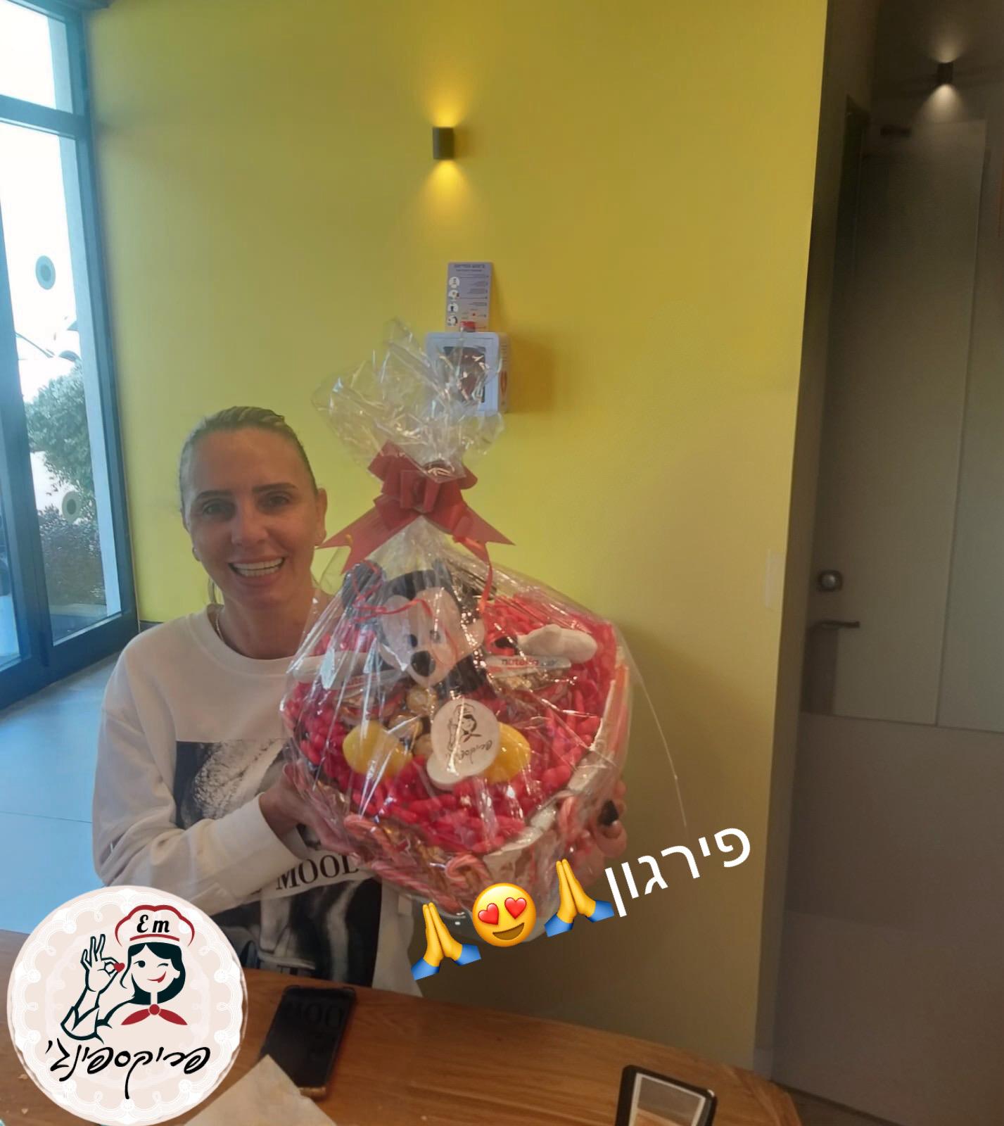 אישה מחייכת ומחזיקה מארז מתנה גדול בצורת לב