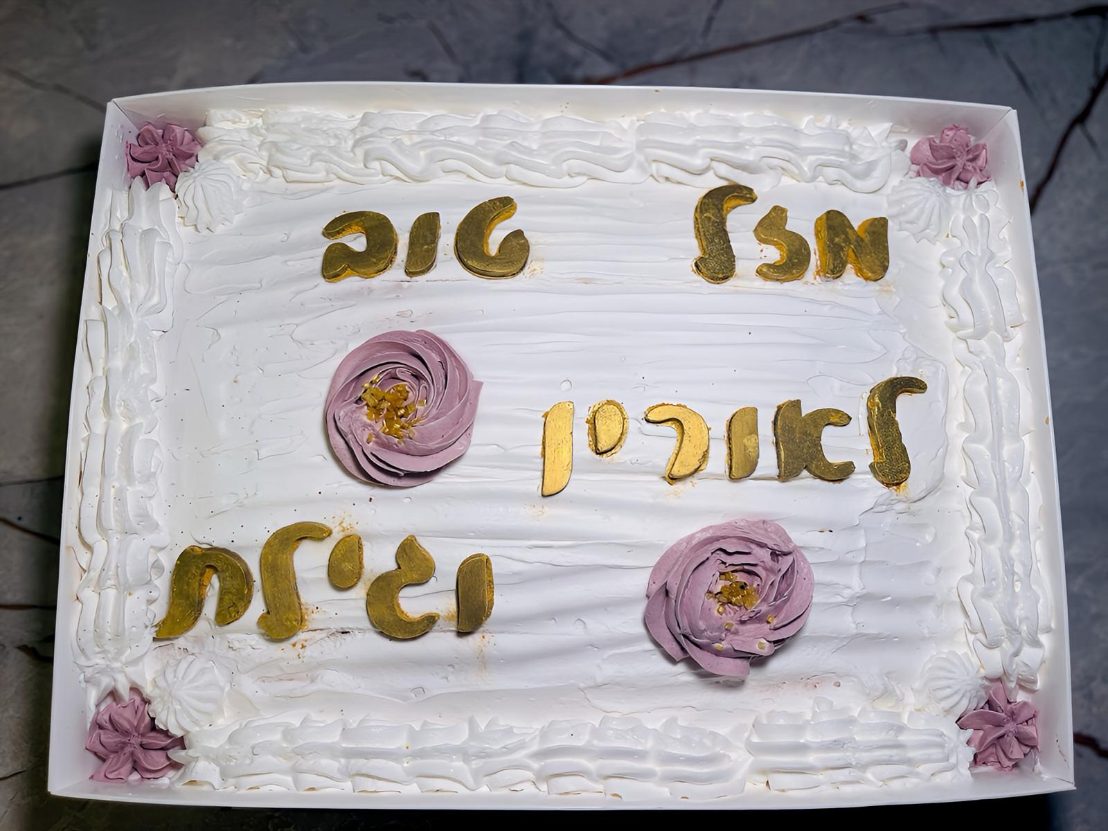 עוגה לבנה מלבנית עם כיתוב מוזהב ועיטורי קצפת