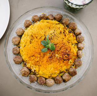 Kalam Polo featuring a perfectly golden and crispy tahdig, surrounded by flavorful meatballs, garnished with fresh mint.