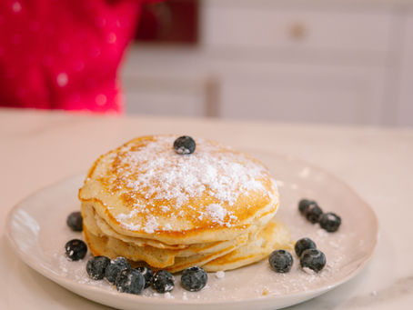 A plate of fluffy pancakes served with powder sugar and blueberries.