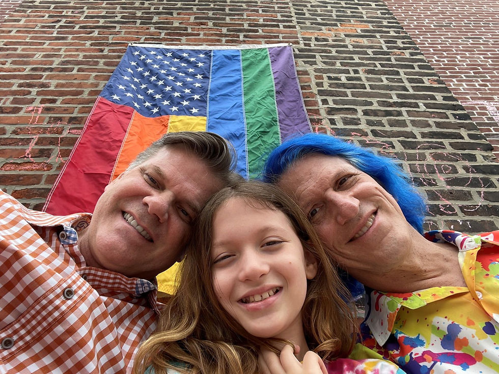 family posing in front of rainbow us flag