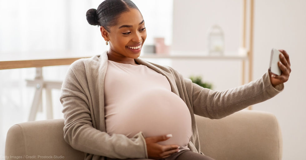 Pregnant woman taking a selfie, smiling at the camera (model). Credit: Getty Images / Prostock-Studio.