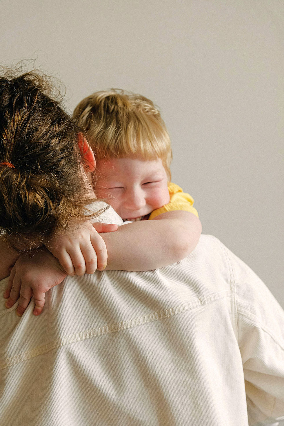 Mother holding toddler while he wraps his hands around her