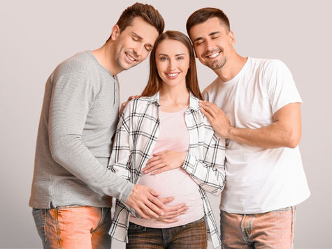 Man and woman embracing a pregnant woman while smiling at the camera (models)