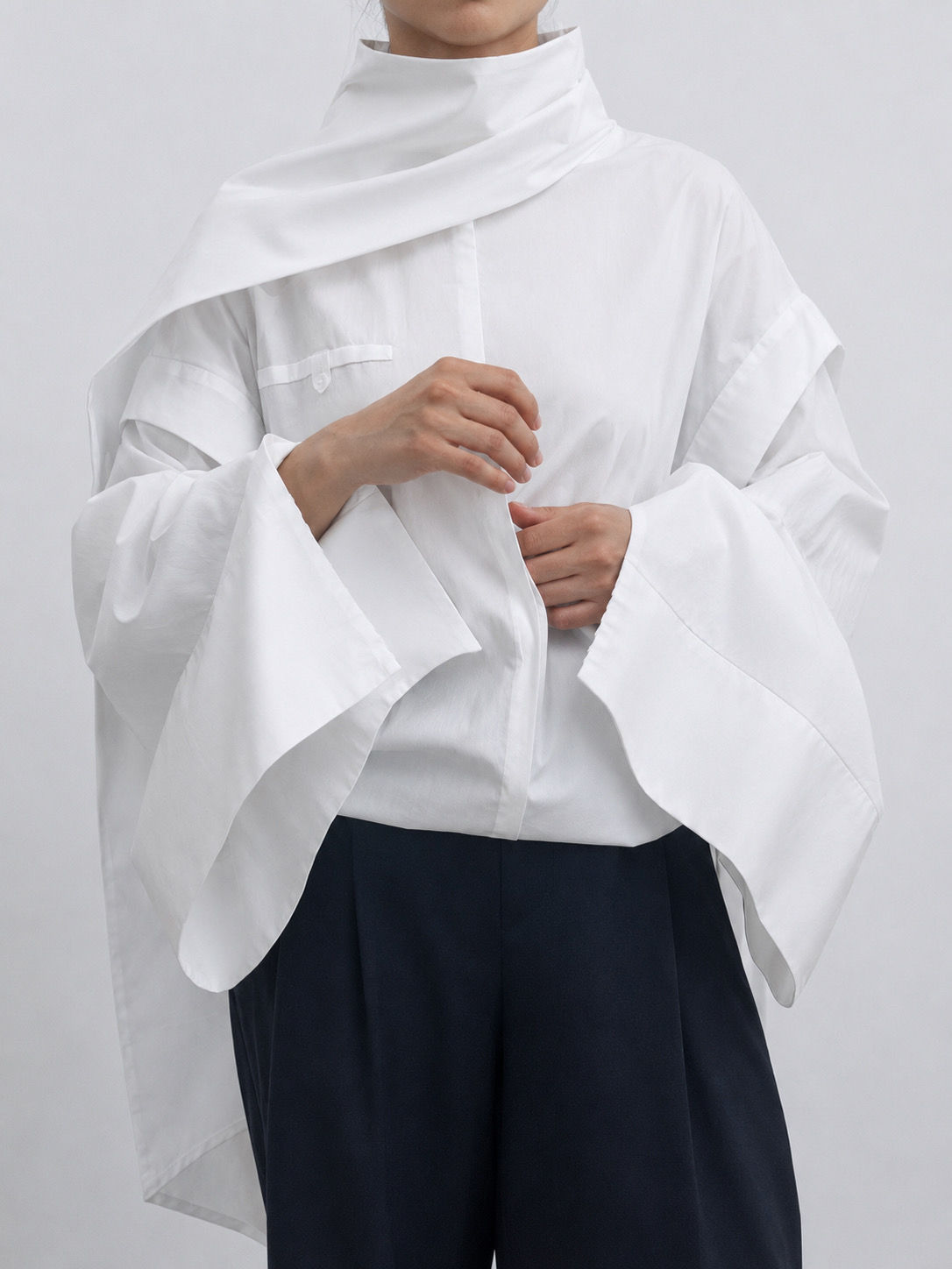 Close-up of the oversized detachable sleeve and cuff detail of the white cotton shirt.