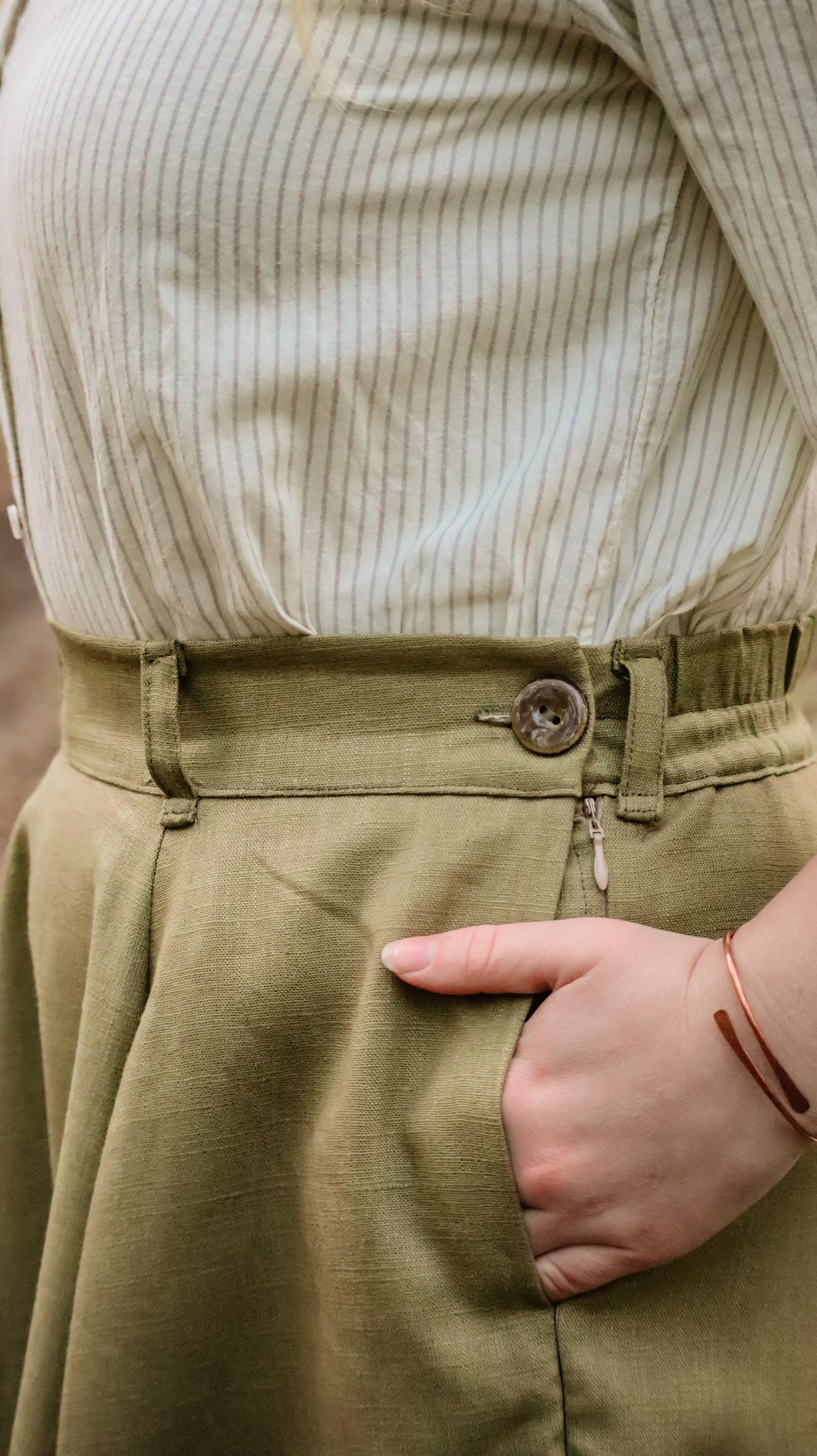 Side view of a green skirt waistband, diplaying a comfortable hand in a side seam pocket