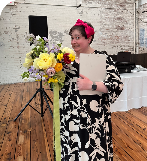 Woman in a black and white dress holding a large bouquet at a wedding event.