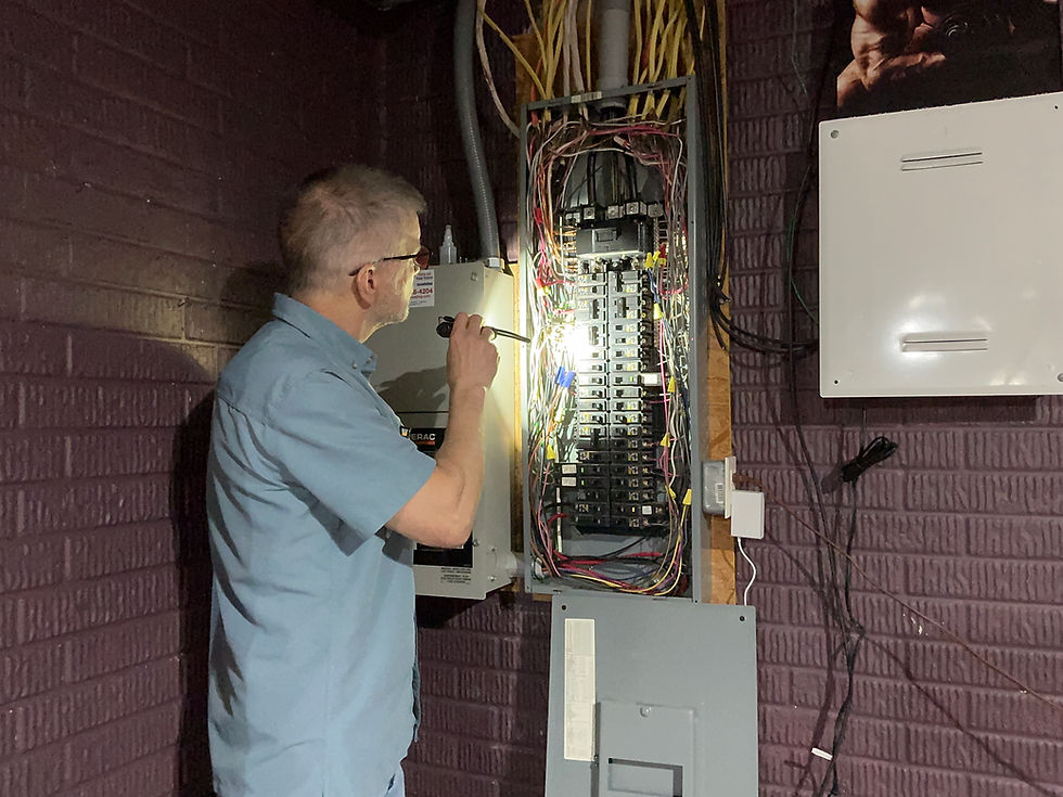 Electrician inspecting an open breaker panel with a flashlight.
