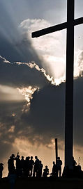 This is an image of people standing underneath a cross