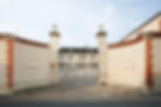 the gate leading into a white brick sampagne house.