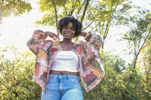 A woman wearing a patchwork quilt jacket outside.