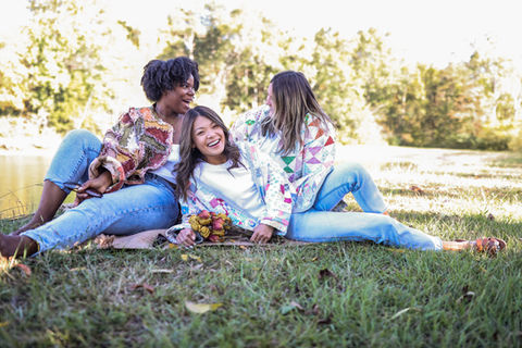 A group of women smiling and laughing wearing quilt jackets.