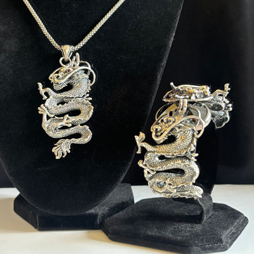 Matching sterling silver dragon pendant displayed beside coordinating dragon cuff bracelet, both featuring eyes & detail work