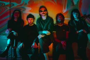Five people (pôt-pot) sit against a vibrant, psychedelic swirl background. They display calm expressions. The scene is colorful and moody.