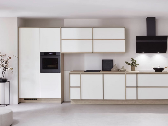 White kitchen with wood-effect edging, a black extractor hood and built-in appliances.