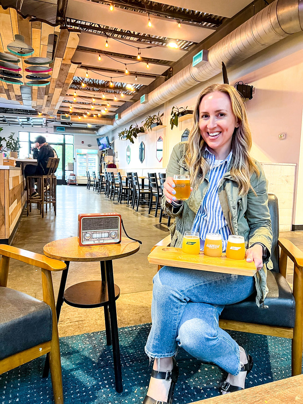Woman holding craft beer flight at Southern Grist Brewing Co's The Nations taproom in Nashville, Tennessee