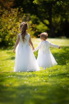 Two Flower girls at a wedding walking along in beautiful white dresses 