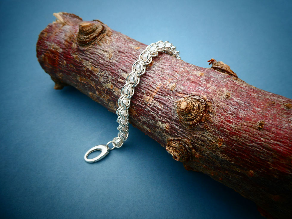 Thumbnail: silver and pearl bracelet artfully draped over wooden log