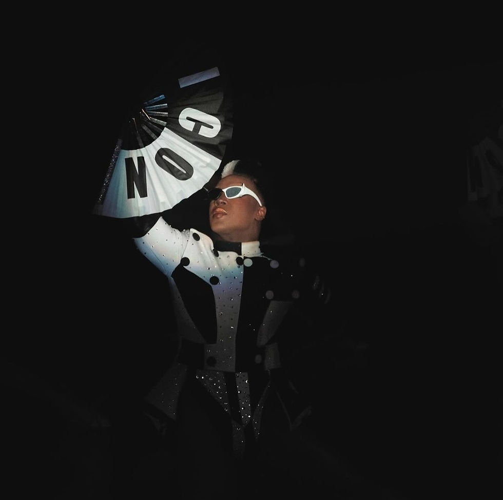 Image of Todrick Hall Wearing black and white costume with black and white shades as well as a black and white fan with the words "ICON" written across.