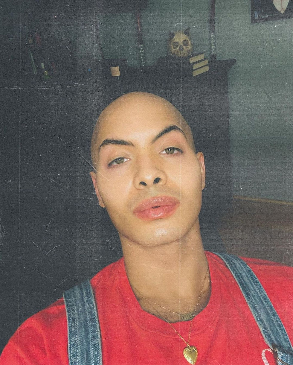 A bust selfie of YouTuber Zzavid wearing a red shirt with jean overalls.