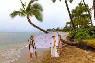 German couple performing the german wedding tradition of Das Hochzeitsherz Ausschneiden on a beach in Oahu Hawaii with Oahu Officiant Nicole Van Diver