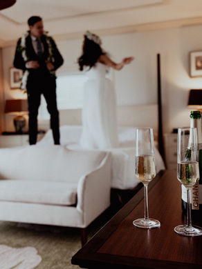 couple playfully jumps on the bed at the kahala resort after getting married in their suite
