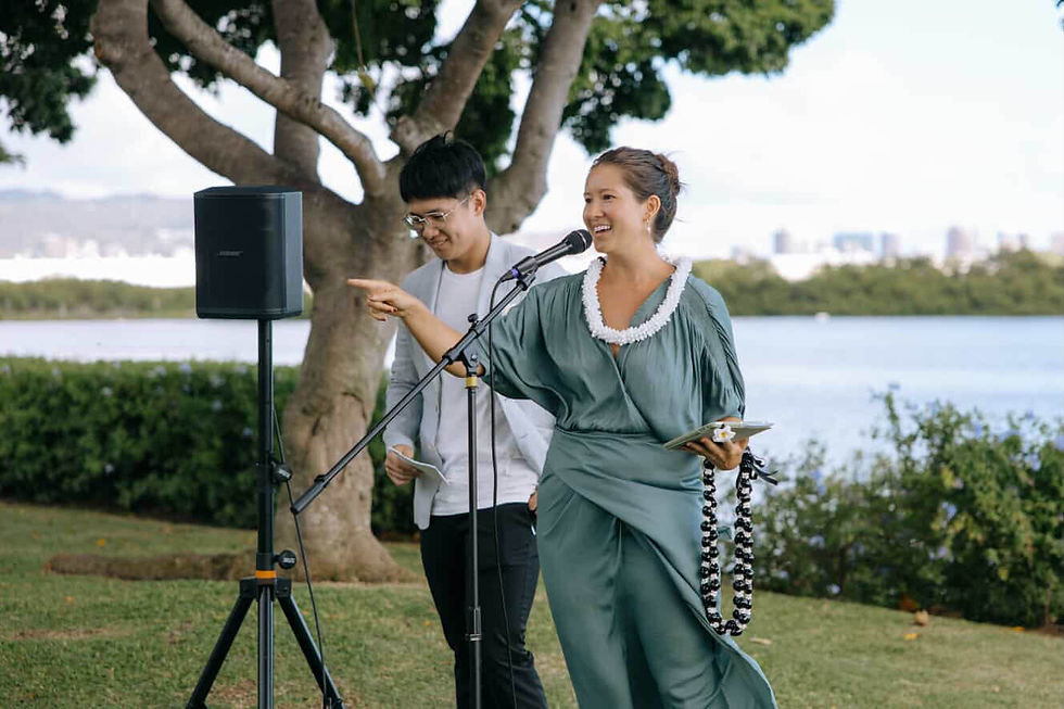 Your Oahu Officiant Nicole Van Diver in front of a microphone at Hanalani Garden wedding venue in Hawaii conducting a wedding ceremony. 