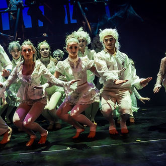 A group of dancers in white costumes are performing on stage.