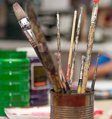 Used paint brushes stand in a tin can, artistic supplies close up view.