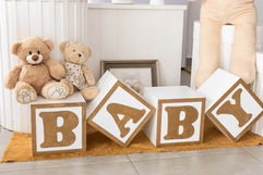 Detalhe decorativo delicado com cubos de madeira formando a palavra baby e ursinhos de pelúcia para chá revelação.