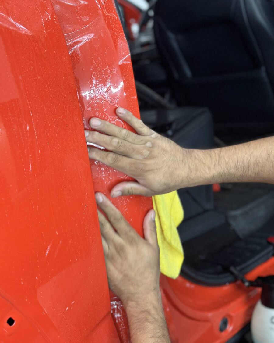Close-up view of paint protection film being applied to a car hood