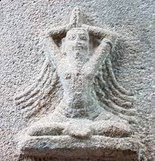 stone carving of seated yogin with mudra and wild hair